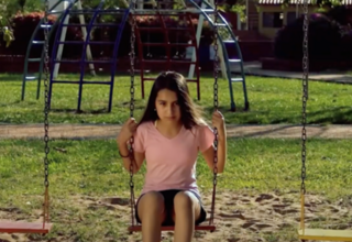 Una adolescente sentada en un columpio en un parque