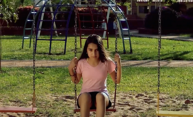 Una adolescente sentada en un columpio en un parque